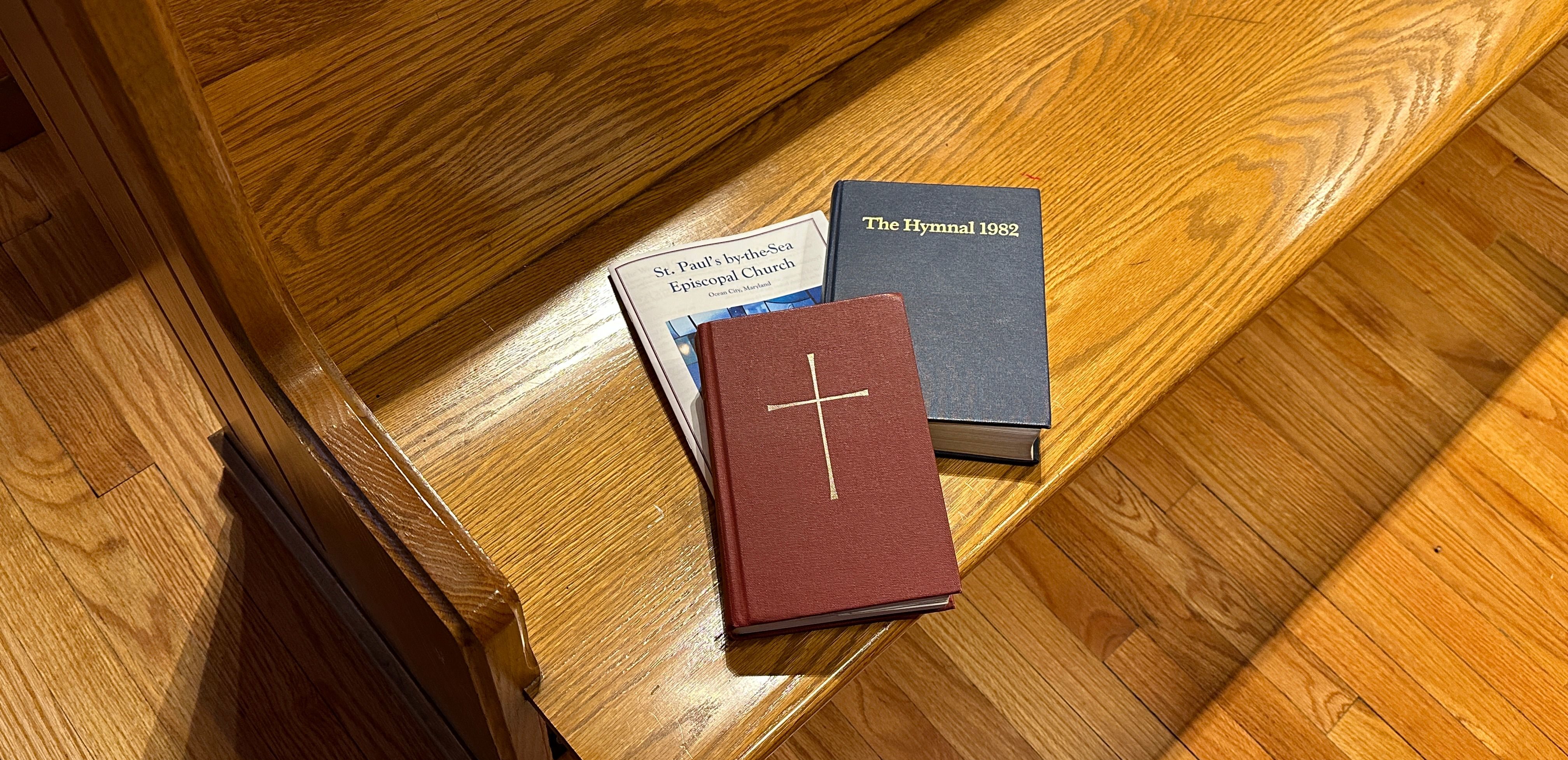 three different colored bibles sitting on a wooden bench