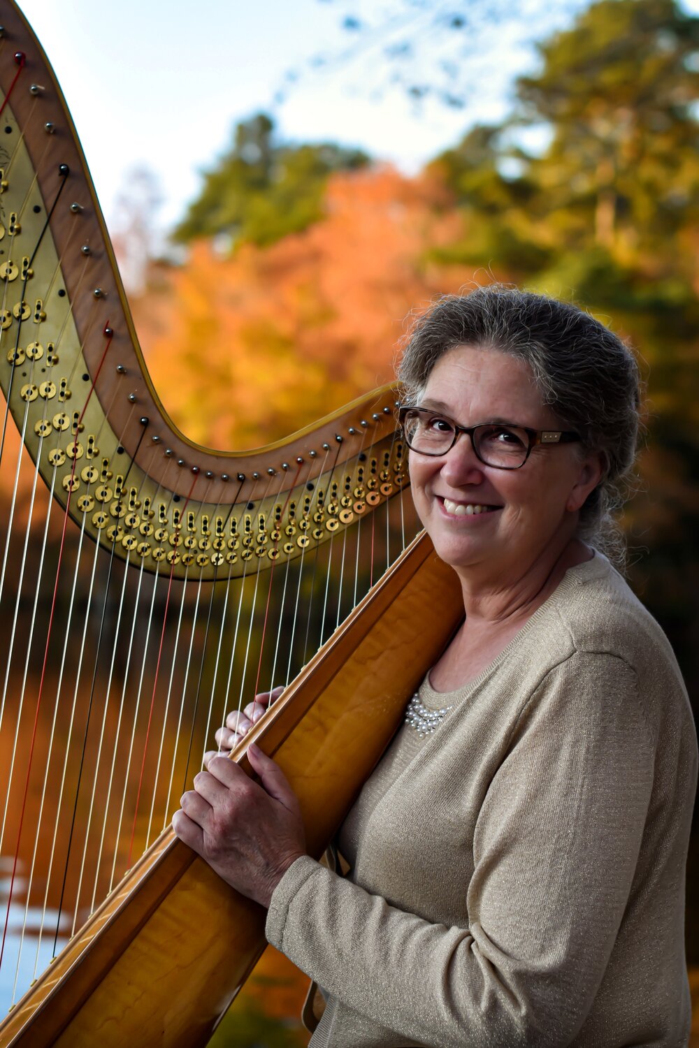 a woman with glasses holding a large harp