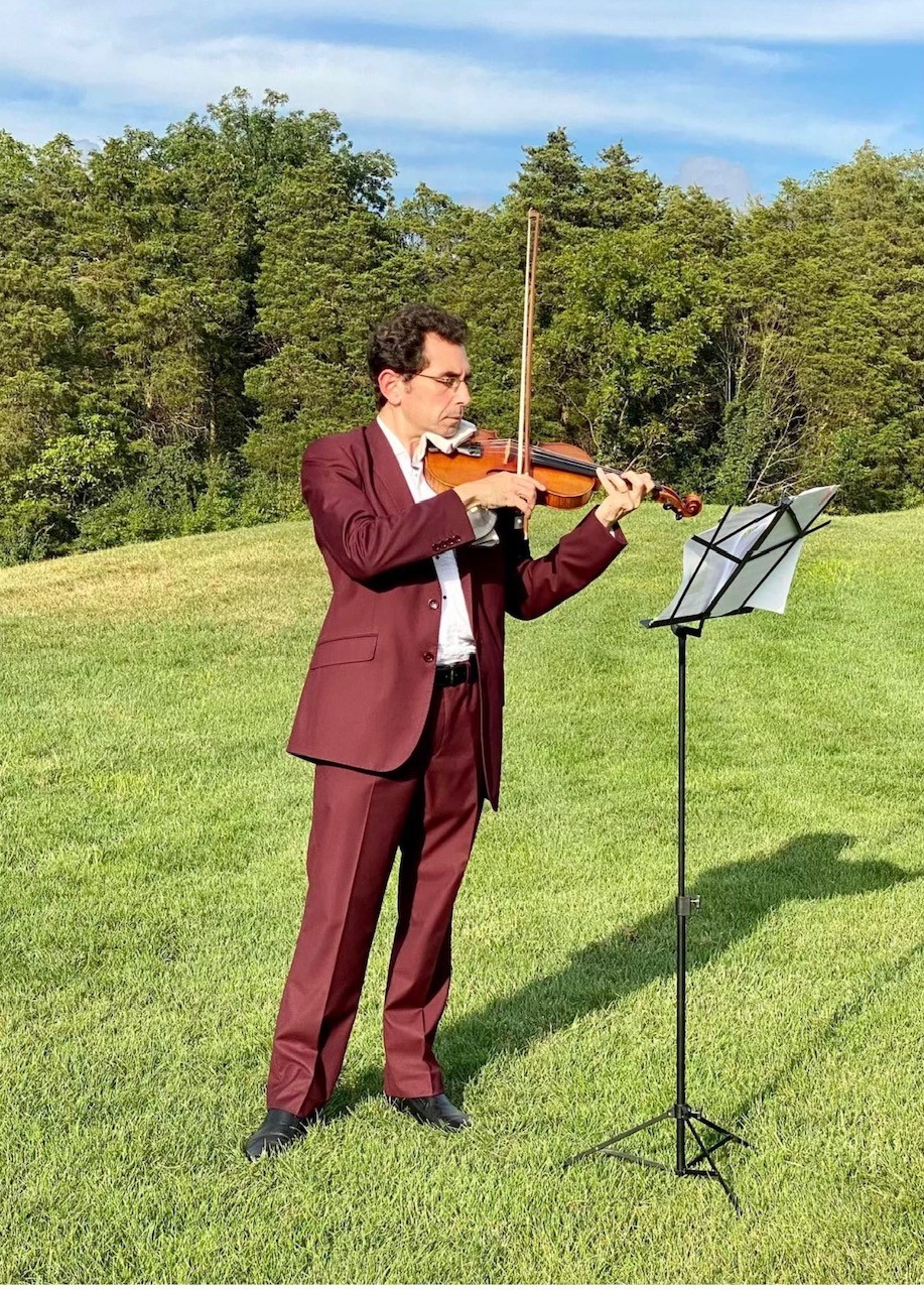 a man in a suit playing violin on the grass