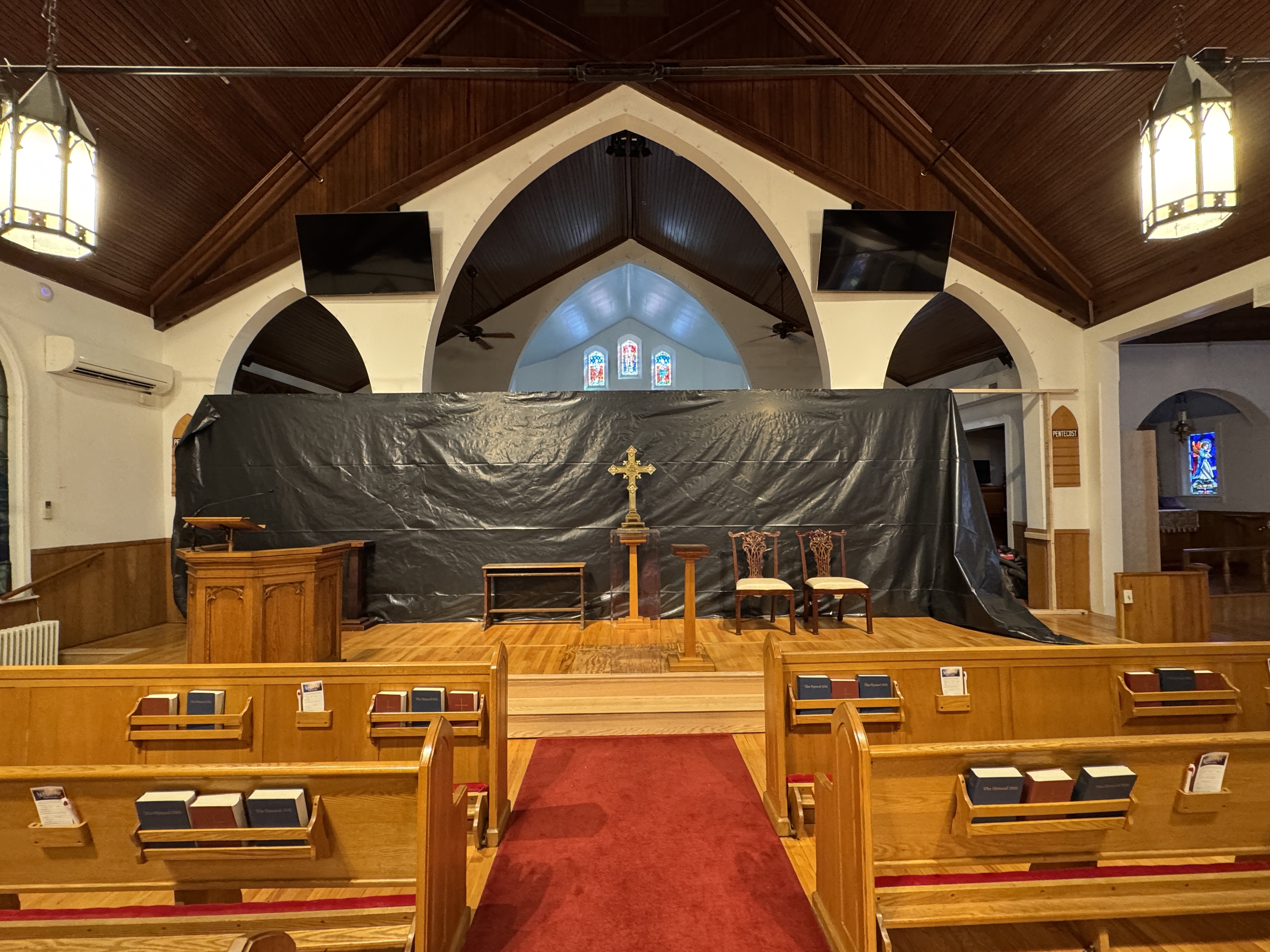 a church with a red carpet and wooden pews